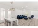 Bright living room features a modern blue sectional couch, a dining table, and wood-look flooring at 9228 Whitekirk Pl, Las Vegas, NV 89145