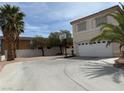 A wide driveway leads to the garage of this two-story residence featuring mature palm trees at 9509 Arrowhead Falls Ct, Las Vegas, NV 89148