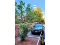 Charming landscaped exterior with pink flowers, mature trees, and a car parked in a private parking spot at , Las Vegas, NV 89118