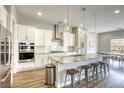Modern kitchen features white cabinets, stainless steel appliances, granite countertops, and a breakfast bar with seating at 11137 Black Fire Opal Dr, Las Vegas, NV 89138