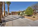 Well-manicured front yard with rock details and a long driveway leading to the attached garage at 6520 Ouida Way, Las Vegas, NV 89108