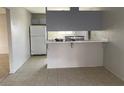 Bright kitchen area with a breakfast bar, tile flooring, and a full-size refrigerator at 709 Scholl Dr, Las Vegas, NV 89107