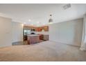 Bright living room with neutral carpeting, stainless steel appliances, and a view into the kitchen area at 757 Omaggio Pl, Henderson, NV 89011