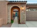 Inviting front entrance featuring a stone archway, accent lighting, and a teal-colored front door at 8113 Bay Colony St, Las Vegas, NV 89131