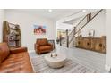 Inviting living room with stylish decor, wood-look floors, leather seating, and a staircase leading to the second floor at 10101 Heron Lake Ave, Las Vegas, NV 89178