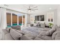 Bright living room with comfortable gray sofa, large sliding glass doors to the pool, ceiling fan, and neutral décor at 10101 Heron Lake Ave, Las Vegas, NV 89178