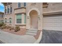 Inviting stucco home features an arched entryway, tidy landscaping, and an attached garage at 10550 W Alexander Rd # 2064, Las Vegas, NV 89129