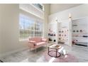 Bright living space with a pink couch, marble floors, built in shelving and large window at 1392 Via Merano St, Henderson, NV 89052