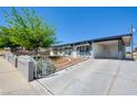 View of the front of this home with a large driveway and mature landscaping in a desert setting at 304 Elliott Ave, Las Vegas, NV 89106