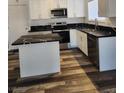 Well-appointed kitchen with white cabinetry, modern appliances, black countertop, and wood-look flooring at 4128 Annie Oakley Dr, Las Vegas, NV 89121