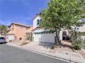 Two-story home showcasing a two-car garage, desert landscaping, and mature trees at 5664 Dawn Falls St, Las Vegas, NV 89148