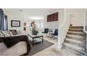 Inviting living room with a modern decor, featuring neutral tones, plush carpeting, and staircase access to the upper level at 6153 Sea Cliff Cove St, North Las Vegas, NV 89031