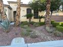 Inviting front exterior featuring desert landscaping with mature plantings, rocks, manicured bushes, and a stone path at 6475 Benbrook Springs Dr, Las Vegas, NV 89131