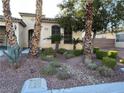 Inviting front exterior featuring desert landscaping with mature plantings, rocks, manicured bushes, and a stone path at 6475 Benbrook Springs Dr, Las Vegas, NV 89131
