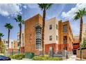 Exterior view of a multi-story condominium building with desert landscaping and tall palm trees at 75 E Agate Ave # 204, Las Vegas, NV 89123