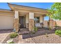 Inviting front porch featuring stone accents, desert landscaping, and decorative iron front door at 797 Drammatico Pl, Henderson, NV 89011