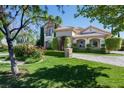 Beautiful two-story home with a well-manicured lawn, lush landscaping, and paved driveway at 9533 Orient Express Ct, Las Vegas, NV 89145
