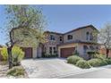 Beautiful two-story home featuring a lush yard, desert landscaping, and multi-car driveway at 9992 Sky Parlor Rd, Las Vegas, NV 89178