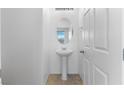 Well-lit half bathroom with a pedestal sink, an oval mirror, and crisp white walls at 10925 Jordyn Hill St, Las Vegas, NV 89141