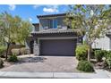 Charming gray home with a two-car garage, a brick driveway, and neatly manicured landscaping at 10925 Jordyn Hill St, Las Vegas, NV 89141