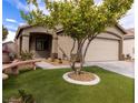 Inviting single-story home with lush, green lawn, mature shade tree, and a two-car garage at 1100 Warm Canyon Way, Las Vegas, NV 89123
