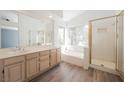 Bright bathroom featuring double sinks, a soaking tub, a separate shower, and large windows at 124 Countrywood Cir, Las Vegas, NV 89107