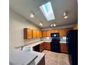 Bright kitchen featuring natural wood cabinets, black appliances, and a skylight for ample natural light at 3538 Old Course St, Las Vegas, NV 89122