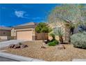 Single-story home featuring a two-car garage and desert-style landscaping with gravel, rocks, and native plants at 7556 Wingspread St, North Las Vegas, NV 89084
