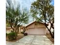 Inviting home exterior with a well-manicured lawn, mature trees, and a spacious two-car garage providing ample parking at 7821 Desert Bell Ave, Las Vegas, NV 89128