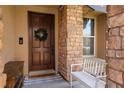 Inviting front entrance features a decorative wreath, stone accents, a cozy bench, and a charming welcome mat at 8537 Eureka Heights Ct, Las Vegas, NV 89178