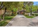 Elegant home featuring a brick driveway, stone archway, and vibrant green lawn at 11814 Canons Brook Dr, Las Vegas, NV 89141