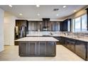 Bright kitchen features dark cabinets, stainless appliances, granite counters, tile backsplash, and a central island at 12391 Pinetina St, Las Vegas, NV 89141
