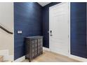 Stylish entryway featuring a white front door, modern console table, and elegant blue textured wallpaper at 5594 Trilling Bird Dr, Las Vegas, NV 89135