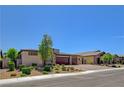 Wide view of the home's front facade displaying desert landscaping and a three-car garage at 7095 Falabella Ridge Ave, Las Vegas, NV 89131