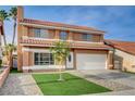 Two story home with terra cotta roof, grassy lawn, small tree and desert landscaping at 8636 Caribbean Ct, Las Vegas, NV 89117