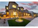 Charming home with stone accents, manicured lawn, and inviting facade at dusk, showing a well-lit driveway at 10372 Thurso Ave, Las Vegas, NV 89166