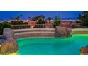Inviting rock-accented backyard pool featuring lights, tile trim and partial Las Vegas skyline view at 11037 Clarion Ln, Las Vegas, NV 89134