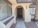 Arched doorway with dark wood door between two windows and a desert landscaped yard at 230 Queen Marie Ct, Henderson, NV 89015