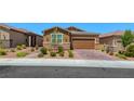 Single-story home with a well-maintained front yard, desert landscaping, a brick driveway and an attached garage at 2767 Flowing Breeze St, Henderson, NV 89044