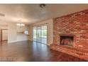 Open living room with a cozy brick fireplace, hardwood floors, and sliding glass doors to the backyard at 4000 Twain Ave, Las Vegas, NV 89121