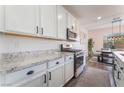 Bright kitchen boasts stainless appliances, white cabinets, and beautiful granite counters at 7132 Sayonara Vista St, North Las Vegas, NV 89084