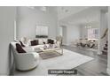 Staged living room featuring gray wood floors, high ceilings, white sofa and chairs, and a modern gold coffee table at 830 Binbrook Dr, Henderson, NV 89052