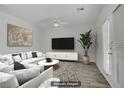 Living room with hardwood floors, a ceiling fan, a comfortable sofa with throw pillows, and a large flat screen television at 830 Binbrook Dr, Henderson, NV 89052
