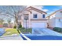 Inviting two-story home, boasting a manicured front lawn and a two-car garage, all under a sunny sky at 9879 Jazzy June St, Las Vegas, NV 89183