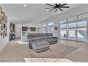 Spacious living room with large windows, tile flooring, a modern ceiling fan, and a comfortable sectional sofa at 2494 Veronella St, Henderson, NV 89044