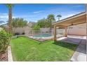 A grassy backyard with a fenced pool, a covered patio and some palm trees at 681 Peach Coral St, Las Vegas, NV 89183