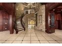 Grand foyer with stone walls, wood trim, tile floors, and a winding staircase leading to the upper level at 1800 Melfi Ct, Henderson, NV 89012