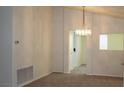 A dining room features neutral walls and carpet, brightened by a decorative chandelier, and offers a glimpse into an adjacent room at 9904 Arbuckle Dr, Las Vegas, NV 89134