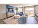 Cozy living room with modern furniture, light hardwood floors, and glass sliding door to the patio at 10382 Luna Mezzo St Ave # Lot 196, Las Vegas, NV 89141