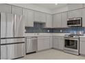 Well-equipped kitchen with stainless steel appliances, stylish blue backsplash, ample cabinetry, and quartz countertops at 1103 Tektite Ave, Henderson, NV 89011
